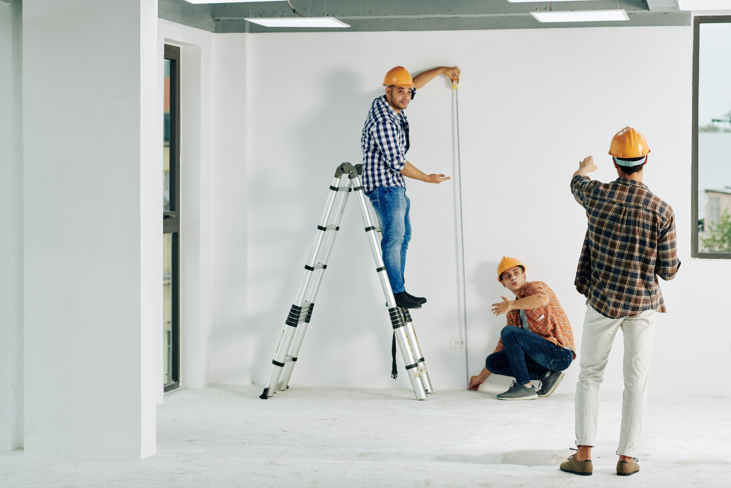 Construction workers measuring wall